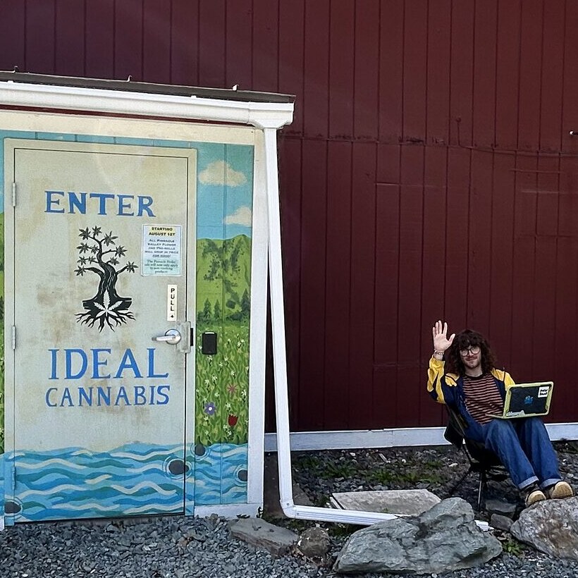 An Ideal budtender waving hello from a chair outside the Ideal Cannabis storefront on Route 14 in Sharon, Vermont